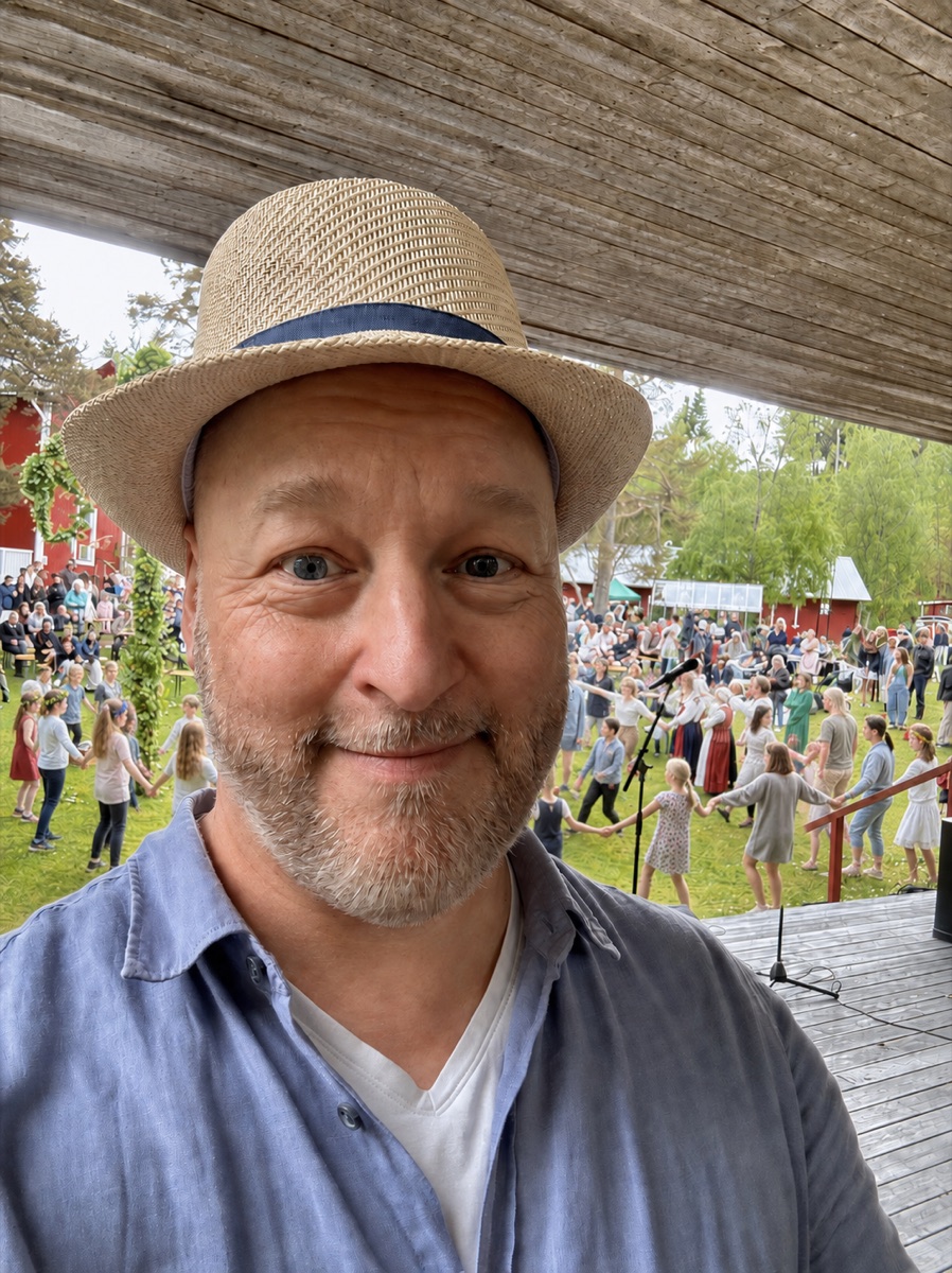 AI-bearbetad stämningsbild: Daniel i stråhatt, med ringdans och midsommarpublik i Klabböle.