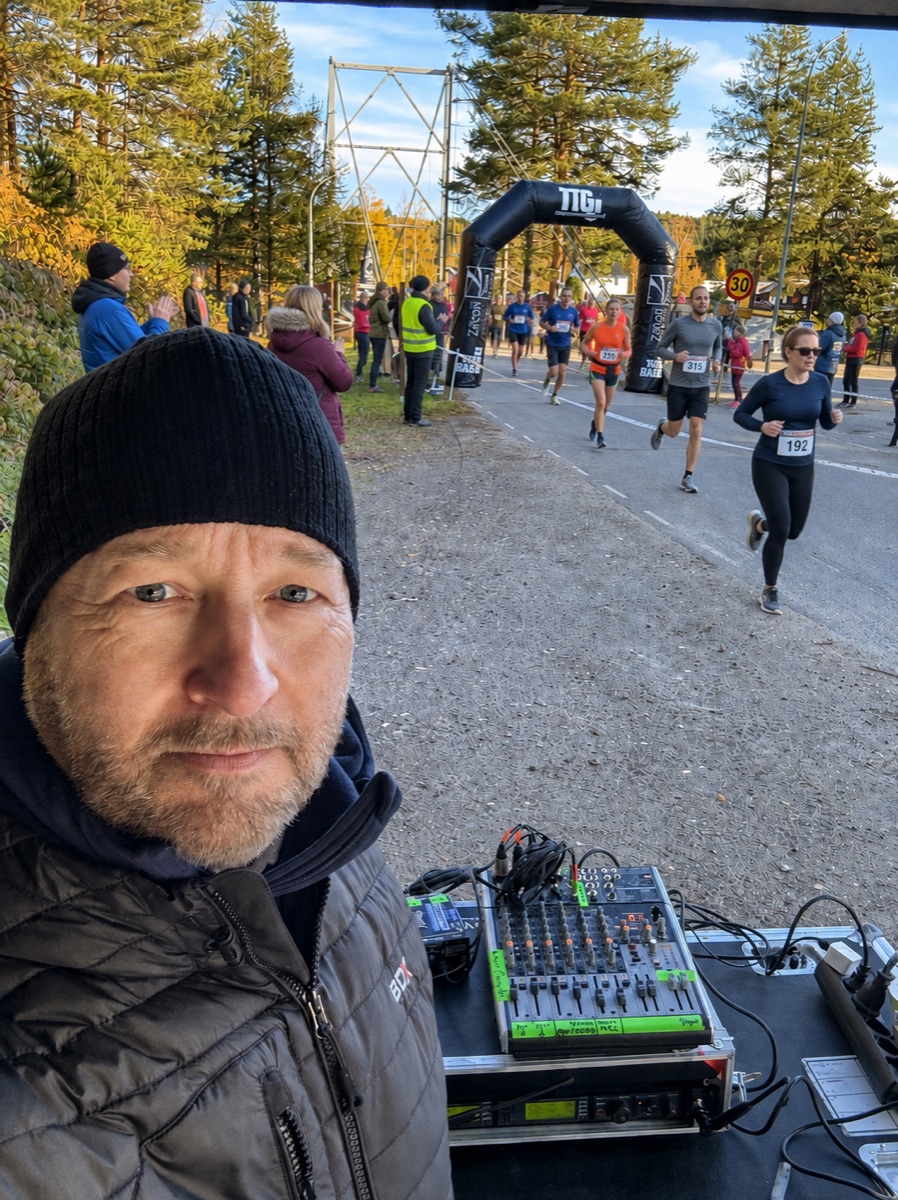 AI-bearbetad stämningsbild: Daniel vid ljudutrustningen, med löpare och hejande åskådare vid målportalen.